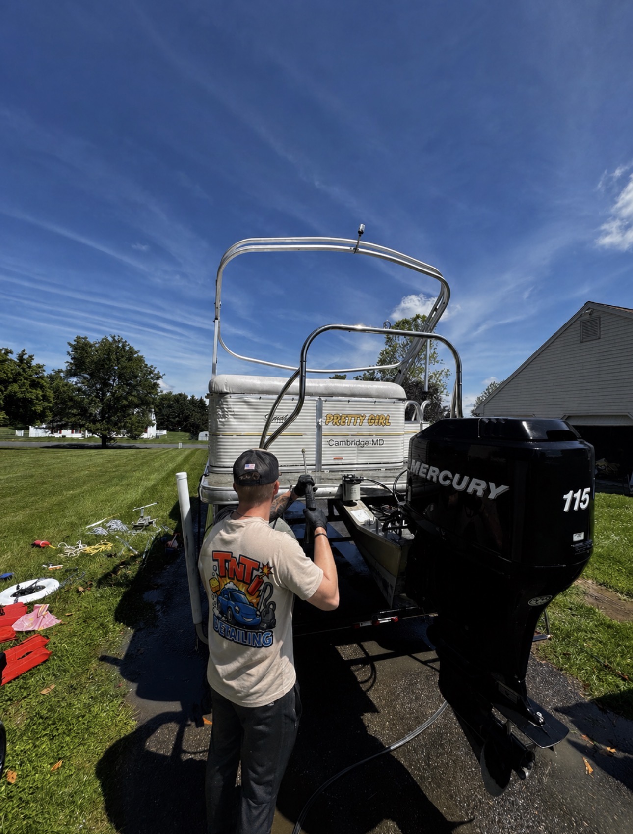 TnT Detailing technician pressure-washing a pontoon boat